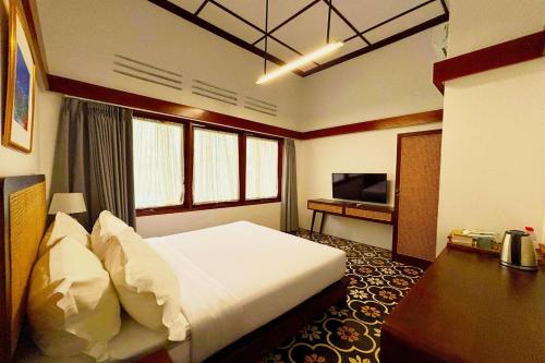 a bedroom with a bed and a desk and a television at Emaki Bumi Singgah in Bandung