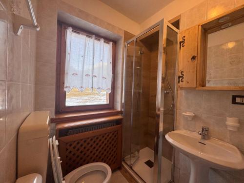 a bathroom with a toilet and a sink and a window at CasaSabry in San Nicolò di Comelico