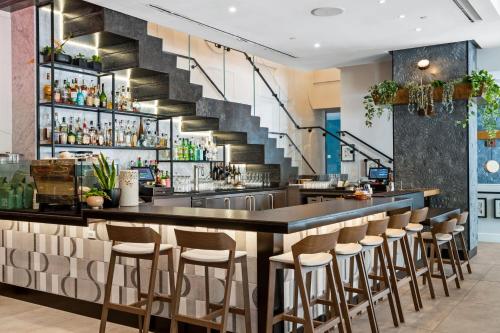 eine Bar mit Hockern in einem Restaurant mit einer Treppe in der Unterkunft Alma San Diego Downtown, a Tribute Portfolio Hotel in San Diego