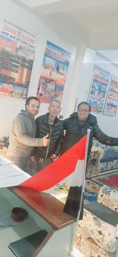 three men standing next to a table with a flag at Grand Square Hostel Luxor in Luxor