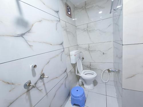 a white bathroom with a toilet and marble walls at Ginger hotels ujjain tower kshipra inn-Family stay airconditioned hotel in Ujjain