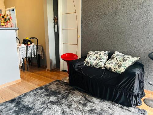 un canapé noir dans un salon avec un tabouret rouge dans l'établissement Cantinho Oliveiras, à Cabo Frio