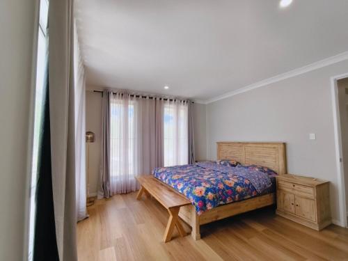 Un dormitorio con una cama y una mesa de madera. en Countryside Hilltop Stay near Gympie, en Corella