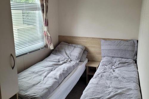 a small bedroom with two beds and a window at Highfield Grange Holiday Park in Clacton-on-Sea
