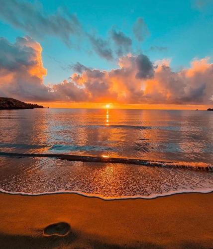 a sunset on a beach with the ocean at Side Sea View D, Steps Away to Bugibba Jetty, For the Blue Lagoon Boats and Other Islands in St Paul's Bay