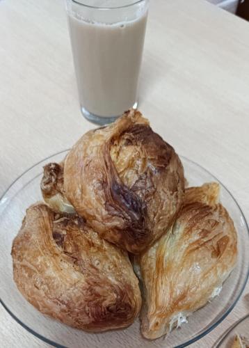 three croissants on a glass plate with a glass of milk at Side Sea View D, Steps Away to Bugibba Jetty, For the Blue Lagoon Boats and Other Islands in St Paul's Bay