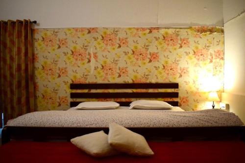 a bedroom with a bed with flowers on the wall at Sudhaksha Celebrations in Prayagraj