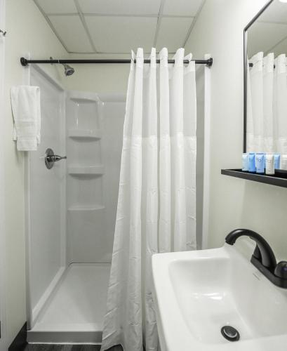 a white bathroom with a shower and a sink at River City Inn in Parsons
