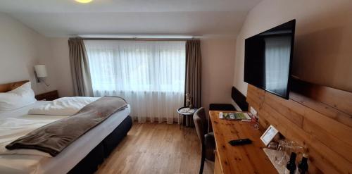 a hotel room with a bed and a flat screen tv at Hotel Restaurant Waldsägmühle in Pfalzgrafenweiler