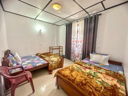 a bedroom with two beds and a chair in it at CLA Holiday Bungalow & Restaurant in Nuwara Eliya