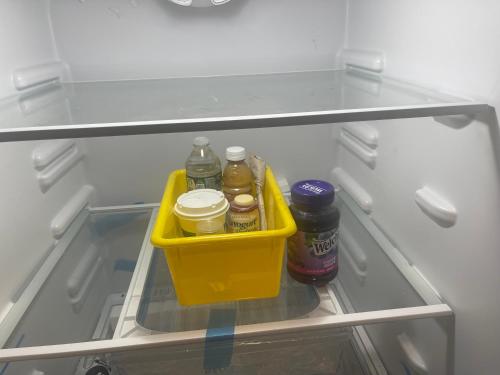 a refrigerator with a yellow crate with bottles and jars at Banlieue Pillars Maison in Mount Vernon