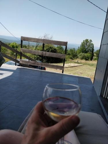 une personne tenant un verre de vin sur une table dans l'établissement Maisonjoske, à Beaulieu