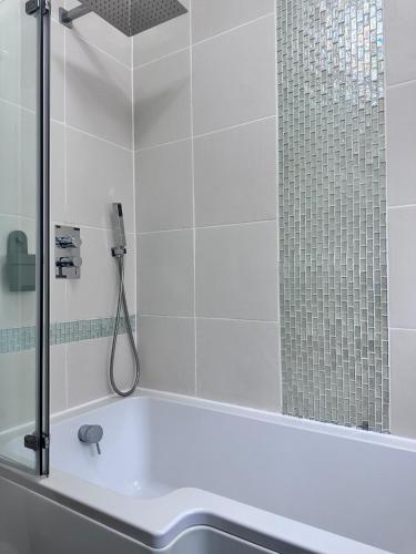 a bath tub with a shower and a sink at No9 Estuary Views in Southend-on-Sea