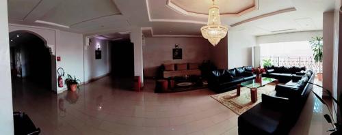 a living room with black leather furniture and a chandelier at Hotel de Fez in Pointe-Noire