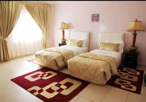 a bedroom with two beds and a rug on the floor at Hotel de Fez in Pointe-Noire