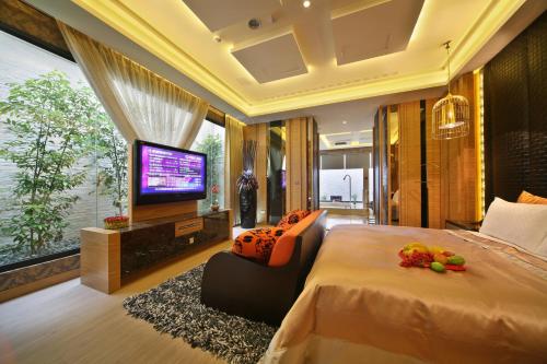 a bedroom with a large bed and a flat screen tv at Han Guan Motel in Taichung