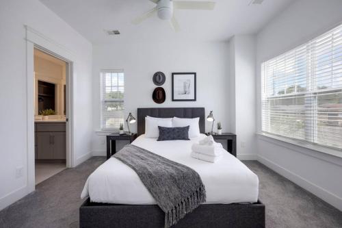 a white bedroom with a large bed and windows at Two Elegant Townhomes Perfect for Large Groups in Nashville