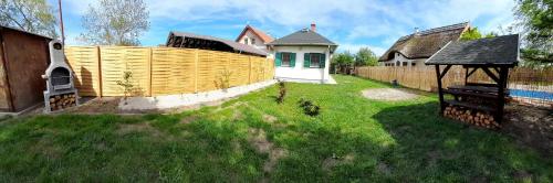a backyard with a wooden fence and a house at Zöld Orom Vendégház in Békésszentandrás