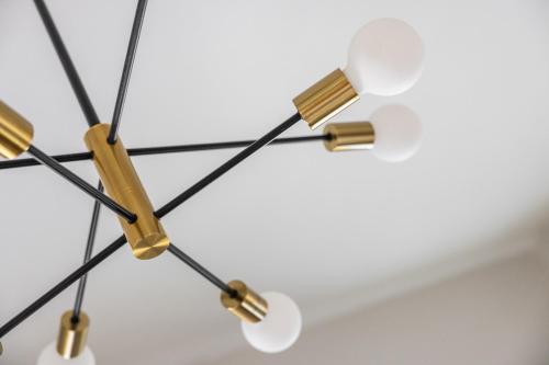 a chandelier with black and gold metals and white fixtures at Mid-Century Modern Retreat in Little Italy in Cleveland