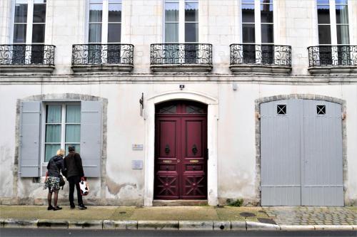 Deux personnes se tiennent devant un bâtiment avec une porte rouge dans l'établissement Résidence des Indes, à La Rochelle