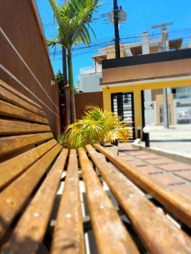 a wooden bench in front of a building with palm trees at Pousada Anjos - à 2 quadras do mar in Matinhos
