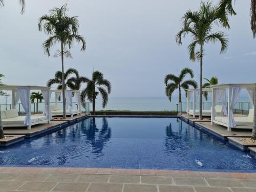 a swimming pool with palm trees and the ocean at Escape to the Pacific of Panama in San Carlos
