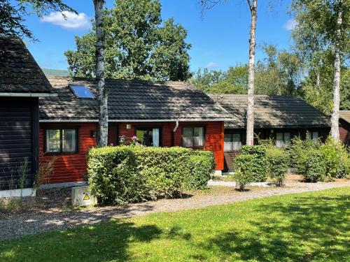 a red house with trees in front of it at Chalet Le Daim La Boverie in Rendeux