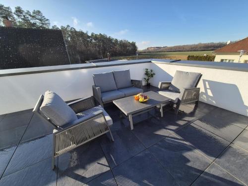 a patio with chairs and a table on a roof at Neubauwohnung mit 80 m2 Terrasse, 8 Minuten von Linz entfernt in Linz