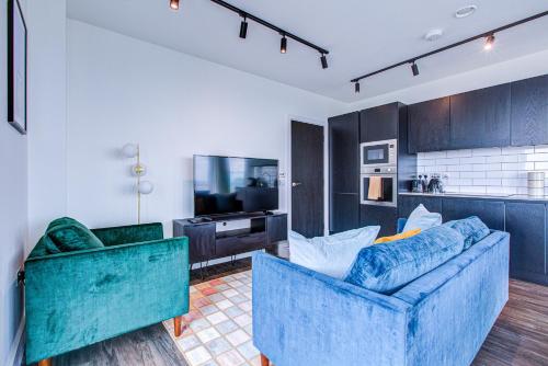 a living room with two blue couches and a kitchen at Legacy Punks by Artsy in London