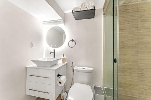 een badkamer met een toilet, een wastafel en een spiegel bij 2 BR ground-level suite in a bungalow with full kitchen, parking, and 20 mins to Downtown in Toronto