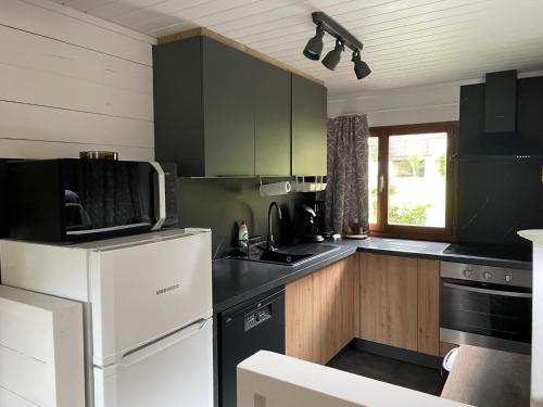 a kitchen with a white refrigerator and wooden cabinets at Chalet Le Daim La Boverie in Rendeux