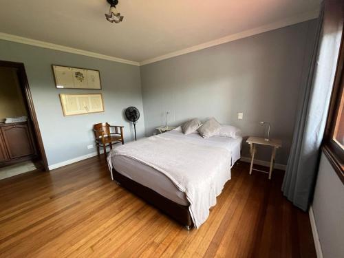 a bedroom with a white bed and a wooden floor at La Casa de los Libros in Pereira