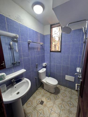 Ein blau gefliestes Badezimmer mit Toilette und Waschbecken in der Unterkunft Beau séjour in Jaunde