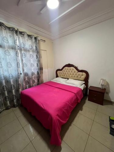 ein Schlafzimmer mit einem großen Bett mit einer rosa Decke in der Unterkunft Beau séjour in Jaunde