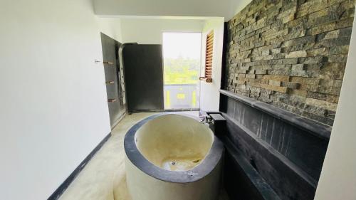 a bath tub in a room with a brick wall at southern grace hotel in Unawatuna