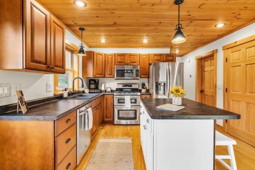a kitchen with wooden cabinets and stainless steel appliances at Private Chalet with Fireplace Hottub and Game Room in Bethel