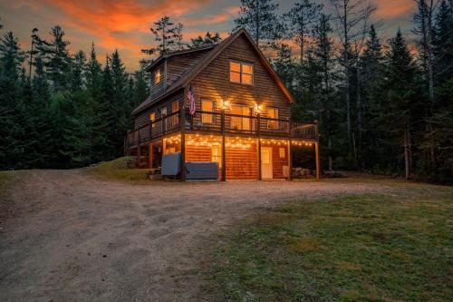 a large wooden house in the woods at sunset at Private Chalet with Fireplace Hottub and Game Room in Bethel