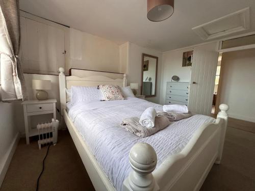 a white bed with towels on it in a bedroom at Rustic Cottage in the countryside in Broadwindsor