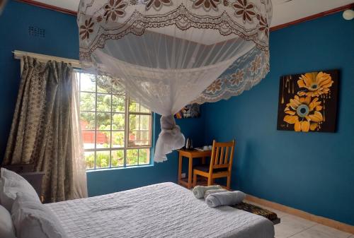 1 dormitorio con paredes azules y 1 cama con ventana en Quest, en Lilongwe
