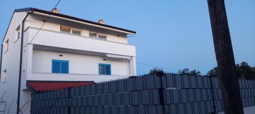 a white building with blue windows and a black fence at VILLA BIANCA - Holiday home with Private pool in Privlaka
