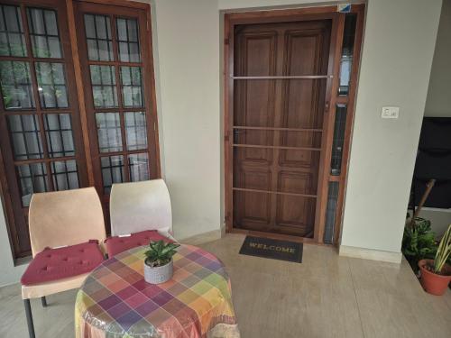 a room with a table and two chairs and a door at Meadows Serene Retreat in Kannur