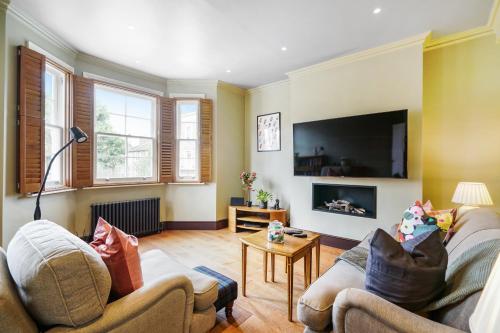 a living room with two couches and a flat screen tv at Beautiful and spacious 2 bed, 2 bath apartment bordering Fulham and Chelsea - entire apartment with private entrance in London