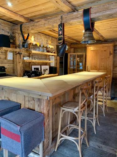 un bar dans une cabane en rondins avec tabourets dans l'établissement Chalet familial et chaleureux, aux Contamines-Montjoie