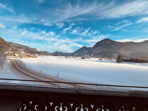 a road in a snowy field with mountains in the background at Chalet Herbst in Lofer