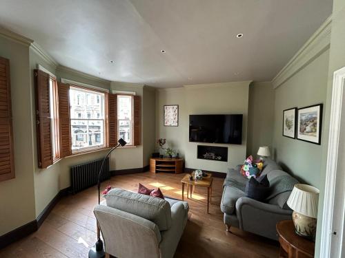 a living room with two couches and a flat screen tv at Beautiful and spacious 2 bed, 2 bath apartment bordering Fulham and Chelsea - entire apartment with private entrance in London