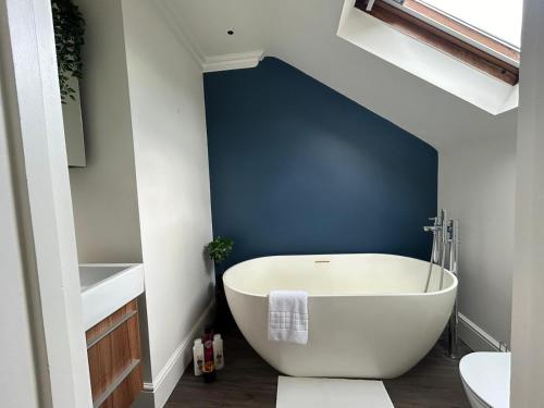 a bath tub in a bathroom with a blue wall at Beautiful and spacious 2 bed, 2 bath apartment bordering Fulham and Chelsea - entire apartment with private entrance in London