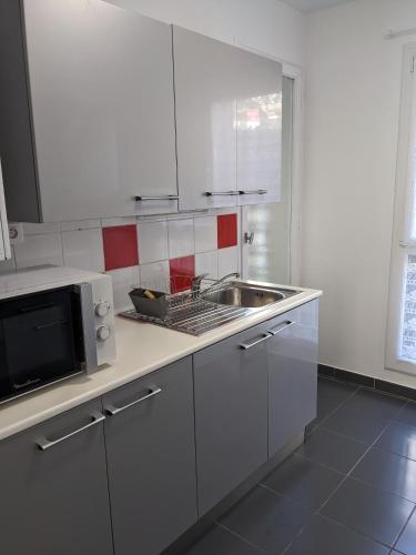 une cuisine blanche avec un évier et un micro-ondes dans l'établissement Appartement T2 meublé classé - secteur petite Provence, à Amélie-les-Bains-Palalda