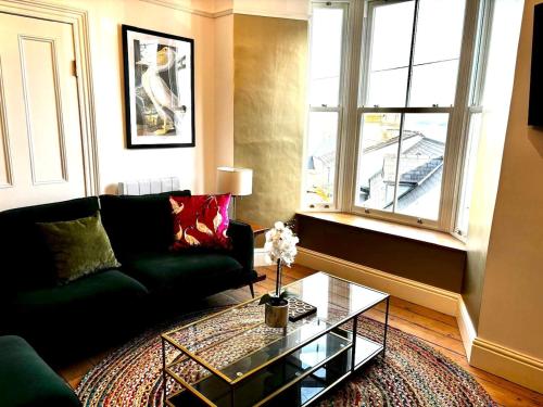 a living room with a green couch and a glass table at Stunning fully refurbished house in New Quay