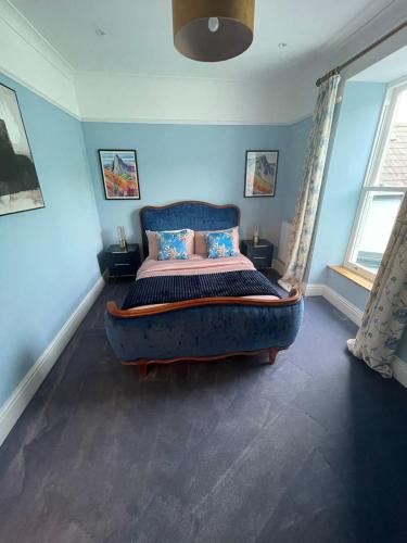 a bedroom with a large bed in a blue room at Stunning fully refurbished house in New Quay
