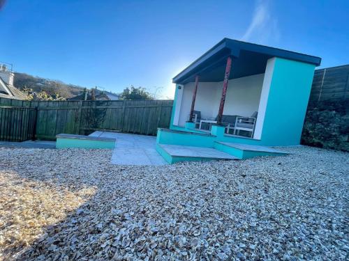 a small blue building with chairs in a yard at Stunning fully refurbished house in New Quay